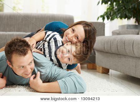 Picture or Photo of Happy family playing at home, lying heaped on floor in living room.
