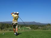 foto of golf  - golfer driving golf ball on beautiful golf course with clear blue sky in the mountains - JPG 