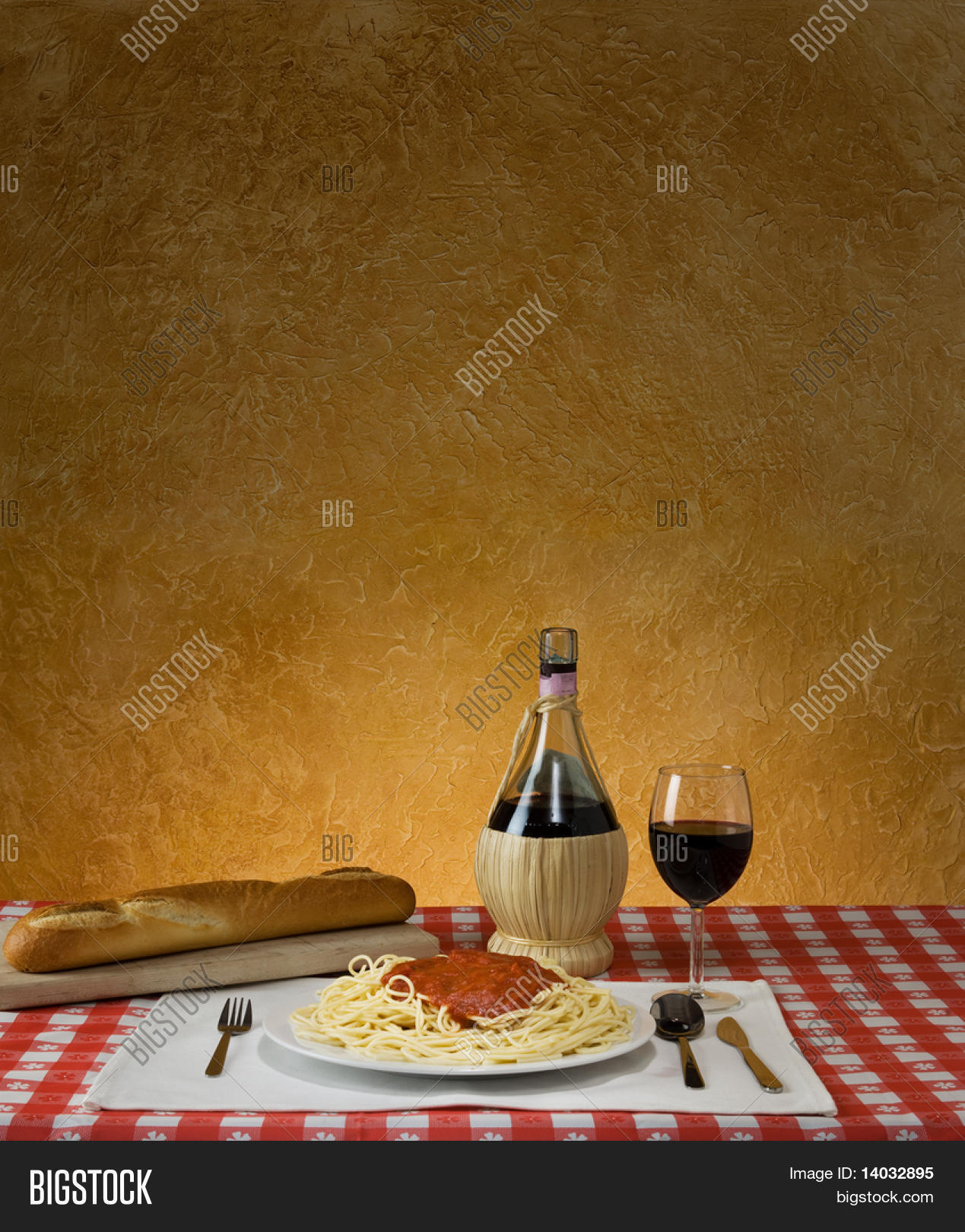 Spaghetti dinner with a baguette and Chianti on a red checkered table