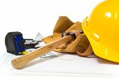 pic of construction worker  - Items used by a construction worker including a leather tool belt a hammer a tape measure tools floor plans and a yellow hard hat - JPG 