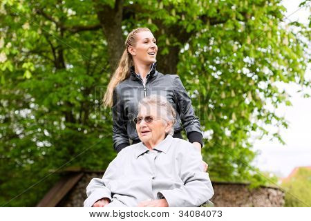 Picture or Photo of Young woman is visiting her grandmother in nursing home having a walk with here in a wheelchair