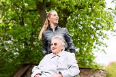 image of home  - Young woman is visiting her grandmother in nursing home having a walk with here in a wheelchair - JPG 