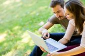 foto of outdoor  - Couple using a laptop outdoors and looking happy - JPG 