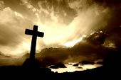 stock photo of religion  - christian cross silhouette and the clouds in sepia tone - JPG 