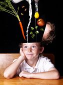 stock photo of food  - young school boy smiling at his desk while his head is being filled with nutritious foods - JPG 