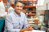 stock photo of businessmen  - Businessman Working At Desk In Warehouse - JPG 