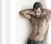 stock photo of fitness  - Beautiful muscular male model with nice abs in jeans near window with copy space - JPG 