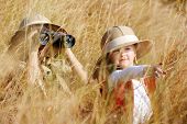 picture of outdoor  - Happy young safari adventure children playing outdoors in the grass with binoculars and exploring together as brother and sister - JPG 