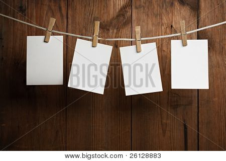 Picture or Photo of Four photo paper attach to rope with clothes pins on wooden background