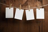 foto of  photo  - four photo paper attach to rope with clothes pins on wooden background - JPG 