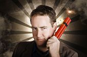 picture of pressure  - Overcome business man waving a lit red bomb with threatening expression when looking to blow up his office block - JPG 