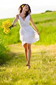 stock photo of health  - Candid skipping carefree adorable woman in field with flowers at summer sunset - JPG 