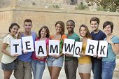 stock photo of teamwork  - Group of young people holding teamwork sign smiling - JPG 