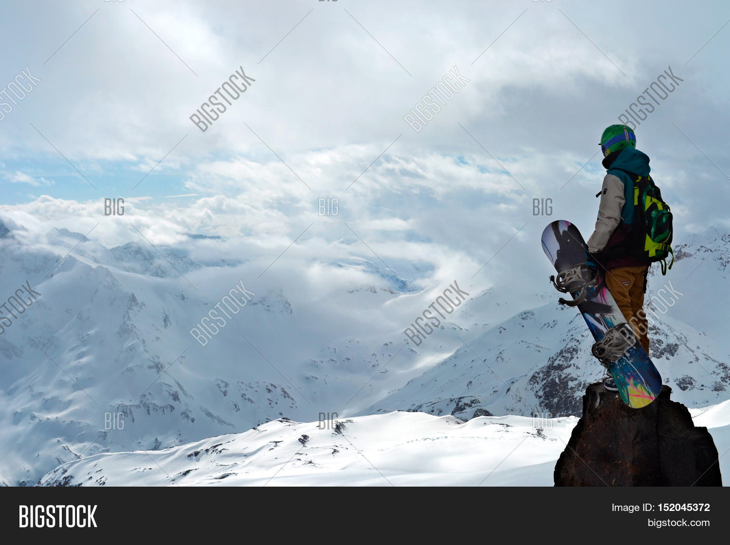 professional snowboarder standing with snowboard in the mountains
