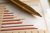 foto of conglomerate  - A gold ballpoint pen on the business page of the newspaper - JPG 