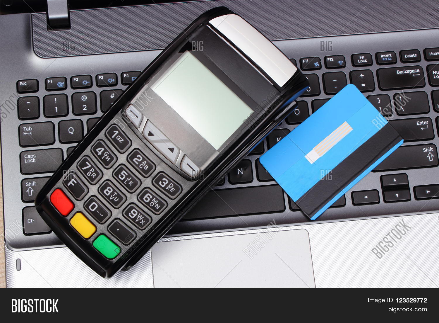 Payment terminal and credit card on laptop keyboard, credit card reader