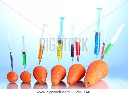 Injection into fresh carrot on blue background