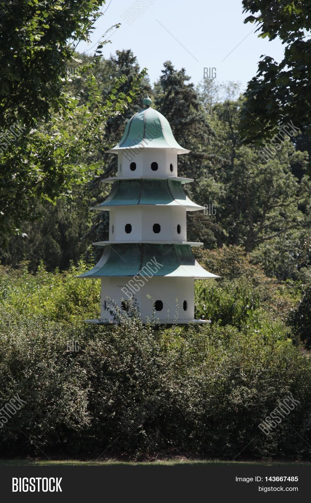 a large three story birdhouse surrounded by trees and a large three story birdhouse surrounded by trees and