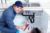 stock photo of workforce  - Mature plumber fixing a sink at kitchen - JPG 