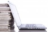 picture of newspaper  - stack of newspaper next to a laptop  - JPG 