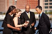foto of group  - A group of business people crowded around a cell phone - JPG 