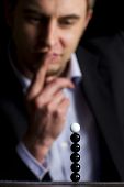 pic of venture  - Business person in dark suit sitting at office desk and looking at stack of balls thinking about new business ventures - JPG 