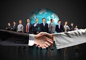 picture of handshake  - business handshake against black background and standing businesspeople - JPG 