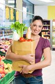 picture of food  - Young woman holding a grocery bag full of fresh and healthy food in a supermarket - JPG 