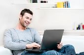 picture of home  - Smiling young man working on laptop at home copy space - JPG 