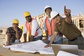 stock photo of construction  - Architect showing blueprint to workers at construction site - JPG 