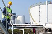 pic of industrial  - Engineer with a clipboard taking notes of the quality and state of oil silos of a petrochemical industry for safety reasons - JPG 