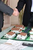 stock photo of handshake  - Handshake over a model housing estate - JPG 