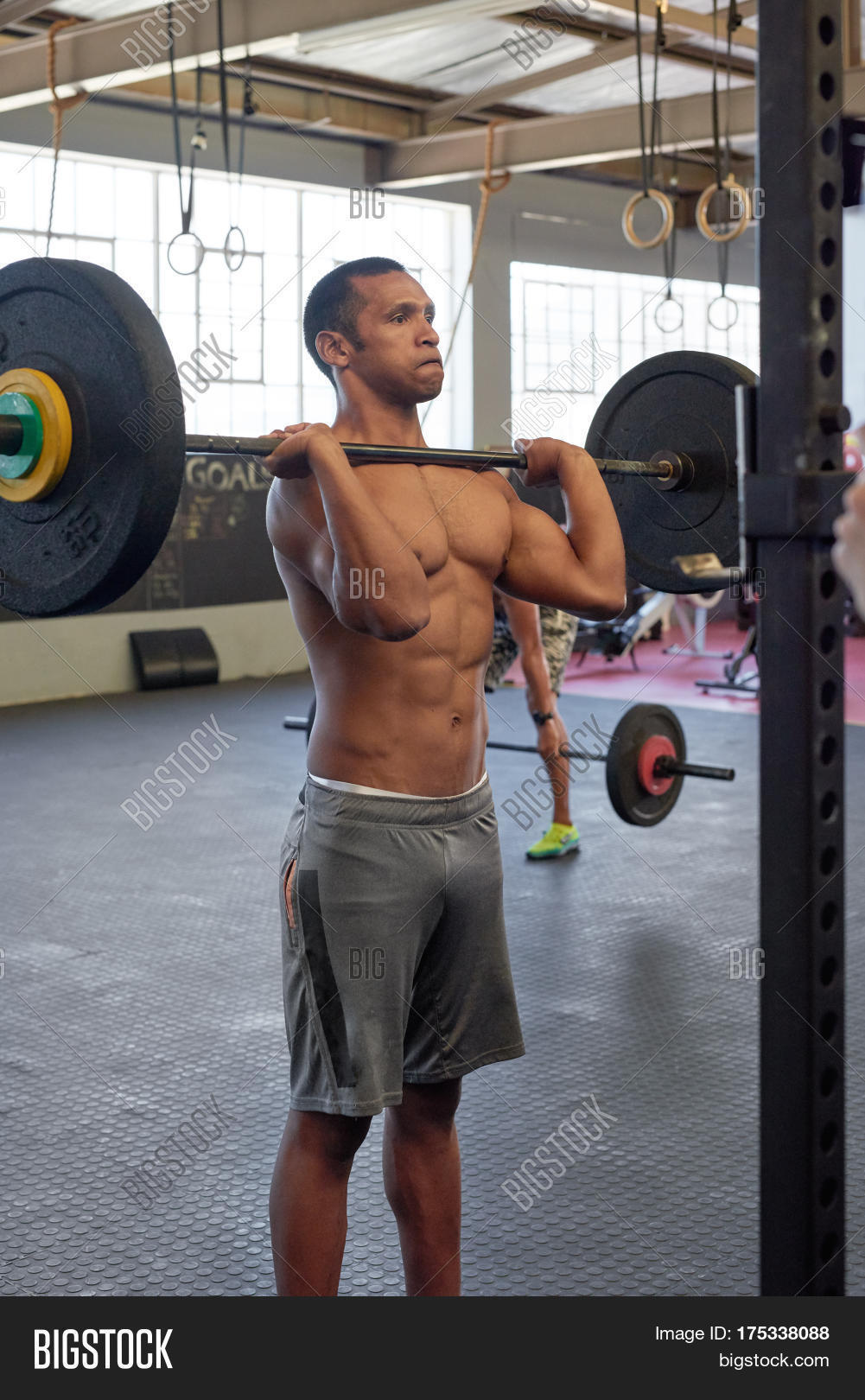 Man working out alone in gym lifting heavy weights to reach personal