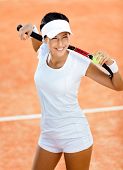 pic of sports  - Woman in sports wear keeps tennis racket and ball on her shoulders at the clay tennis court - JPG 
