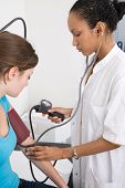 stock photo of bloodpressure  - Doctor measuring the bloodpressure of her patient and listening with the stethoscope - JPG 