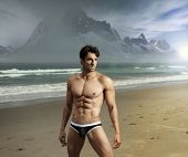 pic of fitness  - Muscular fit sexy guy on remote scenic beach location with dramatic mountains in background - JPG 