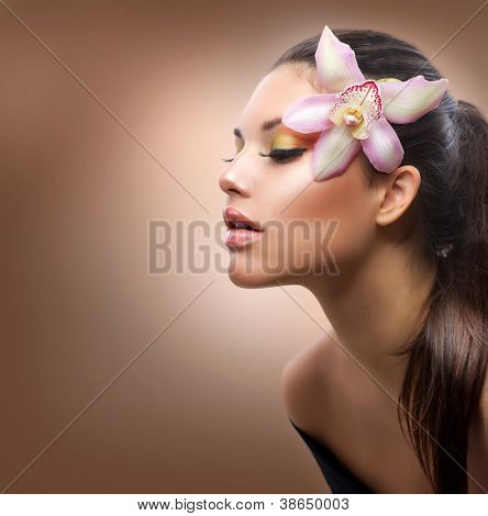 Picture or Photo of Beauty Portrait. Beautiful Stylish Girl with Orchid Flower. Pastel Colors. Perfect Face Skin