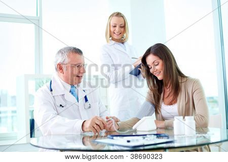 Picture or Photo of Portrait of male practitioner measuring blood pressure of patient with nurse near by