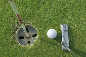 stock photo of golf  - putter puts a golf ball to hole on green of golf course - JPG 