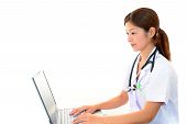 stock photo of medical doctors  - Doctor is sitting on her desk and typing on laptop - JPG 