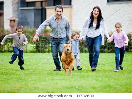Picture or Photo of Happy family running with their dog outdoors
