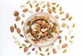 Dried fruits and variety of nuts in a bowl on the white table background, such as figs, almonds, raisins, cashews, and pistachio. with copy space for your text.