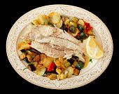 Fish fillet baked with vegetables, Italian dish in traditional plate isolated on black background