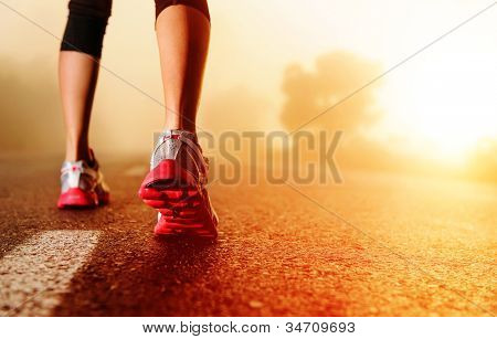 Picture or Photo of Athlete runner feet running on road closeup on shoe. woman fitness sunrise jog workout wellness concept.