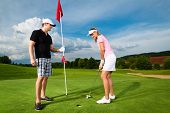 picture of golf  - Young sportive couple playing golf on a golf course - JPG 