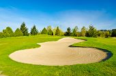 picture of golf  - Sand bunker on the golf course with green grass and trees over blue sky - JPG 