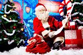 picture of present  - Santa Claus posing with a list of presents over Christmas background - JPG 