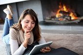 stock photo of comfort  - Woman using digital tablet laying by fireplace - JPG 