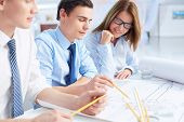 stock photo of meeting  - Team of engineers discussing blueprint at meeting - JPG 
