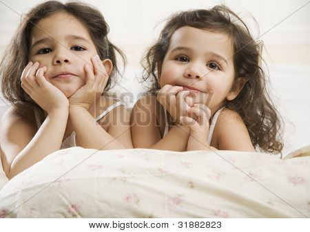 Two young Hispanic sisters in bed - Stock Image - Everypixel